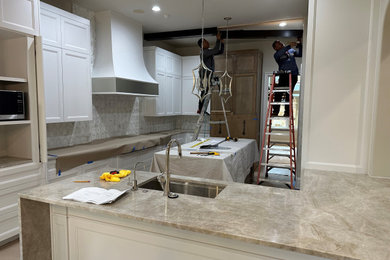 Eat-in kitchen - large u-shaped light wood floor, gray floor and exposed beam eat-in kitchen idea in Dallas with an undermount sink, paneled appliances, an island and beige countertops