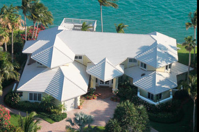 Large yellow two-story exterior home photo in Tampa with a tile roof and a white roof