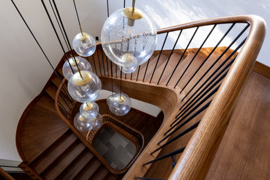 Идея дизайна: большая изогнутая деревянная лестница в стиле кантри с деревянными ступенями и деревянными перилами