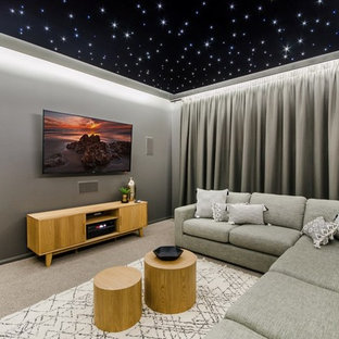 Mid-sized minimalist enclosed carpeted and gray floor home theater photo in Townsville with gray walls and a wall-mounted tv