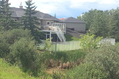 Design ideas for a large partial sun backyard retaining wall landscape in Calgary for summer.