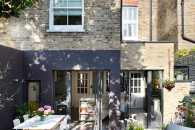 Medium sized contemporary back patio in London with a bbq area, natural stone paving and no cover.