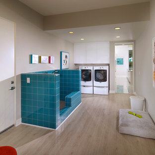 ロサンゼルスのミッドセンチュリースタイルのおしゃれな家事室 (フラットパネル扉のキャビネット、白いキャビネット、グレーの壁、淡色無垢フローリング、左右配置の洗濯機・乾燥機) の写真