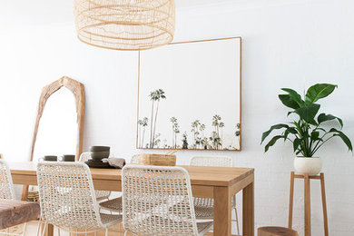 Inspiration for a beach style dining room in Brisbane with white walls, medium hardwood floors and brown floor.