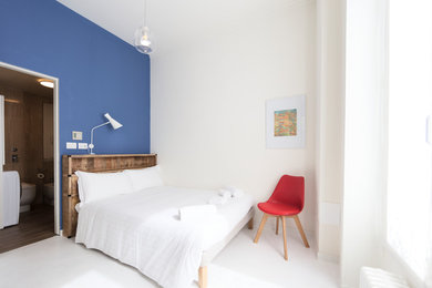 Small contemporary loft-style bedroom in Milan with blue walls, painted wood floors and white floor.
