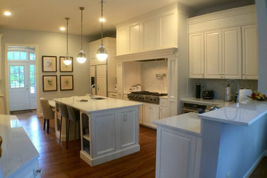 Large transitional u-shaped medium tone wood floor open concept kitchen photo in DC Metro with an undermount sink, raised-panel cabinets, white cabinets, quartzite countertops, stainless steel appliances and an island