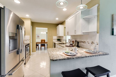 Enclosed kitchen - small transitional galley ceramic tile enclosed kitchen idea in Detroit with shaker cabinets, white cabinets, white backsplash, ceramic backsplash and stainless steel appliances