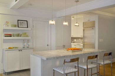 Example of a mid-sized transitional galley open concept kitchen design in New York with a single-bowl sink, shaker cabinets, white cabinets, quartzite countertops, gray backsplash, stainless steel appliances, an island and glass tile backsplash