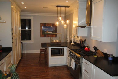 Enclosed kitchen - mid-sized galley dark wood floor enclosed kitchen idea in Chicago with shaker cabinets, white cabinets, granite countertops, white backsplash, stainless steel appliances and a peninsula