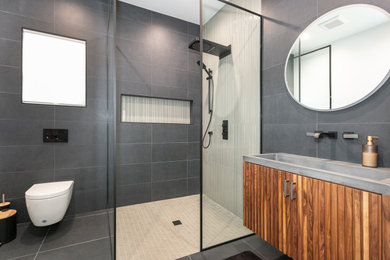 Example of a mid-sized gray tile and porcelain tile porcelain tile, gray floor and single-sink bathroom design in Los Angeles with dark wood cabinets, a wall-mount toilet, white walls, a trough sink and a floating vanity