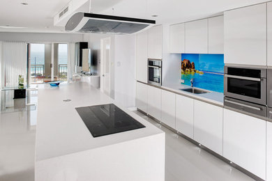 Photo of a mid-sized contemporary single-wall eat-in kitchen in Perth with an undermount sink, flat-panel cabinets, white cabinets, quartz benchtops, multi-coloured splashback, glass sheet splashback, stainless steel appliances, ceramic floors and with island.