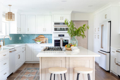 Beach style kitchen photo in Orlando with an undermount sink, white cabinets, quartz countertops, blue backsplash and white appliances