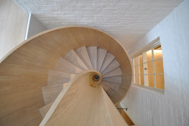 Inspiration for a medium sized wood spiral wood railing staircase in London with wood risers.