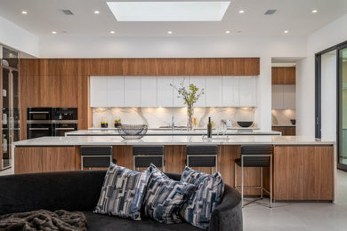 Eat-in kitchen - large modern l-shaped porcelain tile eat-in kitchen idea in San Diego with flat-panel cabinets, white cabinets, quartz countertops, white backsplash, marble backsplash, black appliances, an island and white countertops