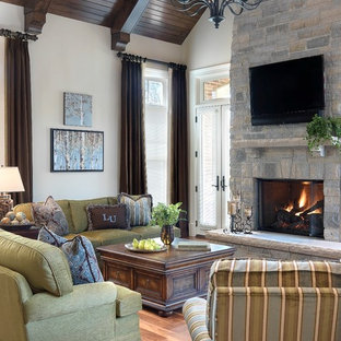Inspiration for a timeless medium tone wood floor family room remodel in St Louis with beige walls, a standard fireplace, a stone fireplace and a wall-mounted tv