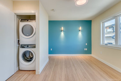 Laundry closet - modern laminate floor and beige floor laundry closet idea in Vancouver with blue walls and a stacked washer/dryer