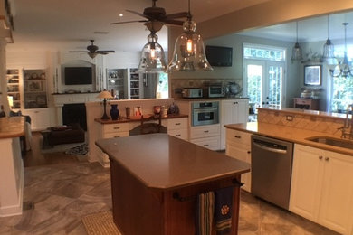 Photo of a mid-sized transitional u-shaped eat-in kitchen in Richmond with an undermount sink, quartz benchtops, beige splashback, stone tile splashback, stainless steel appliances, raised-panel cabinets, white cabinets, porcelain floors and with island.