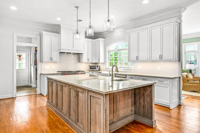 Example of a large classic medium tone wood floor and brown floor eat-in kitchen design in DC Metro with a farmhouse sink, beaded inset cabinets, white cabinets, quartzite countertops, white backsplash, ceramic backsplash, stainless steel appliances, an island and beige countertops