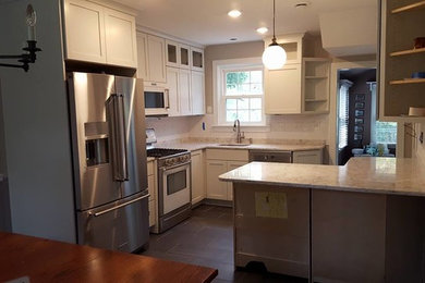 Example of a mid-sized transitional l-shaped porcelain tile and black floor enclosed kitchen design in Baltimore with an undermount sink, shaker cabinets, white cabinets, quartzite countertops, stainless steel appliances, a peninsula and white countertops