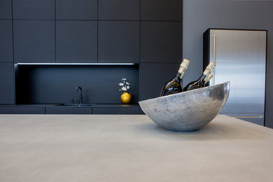 Offene, Zweizeilige Moderne Küche mit Einbauwaschbecken, flächenbündigen Schrankfronten, schwarzen Schränken, Betonarbeitsplatte, Küchenrückwand in Schwarz, Küchengeräten aus Edelstahl, Zementfliesen für Boden, Kücheninsel, grauem Boden und grauer Arbeitsplatte in Frankfurt am Main