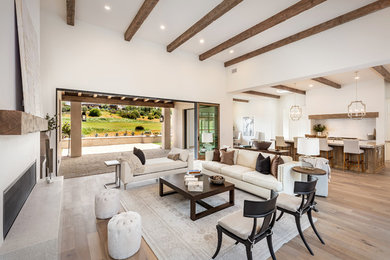 This is an example of a country open concept living room in San Diego with white walls, light hardwood floors, a ribbon fireplace and beige floor.