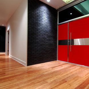ダラスの大きい片開きドアコンテンポラリースタイルのおしゃれな玄関ドア (竹フローリング、白い壁、赤いドア、茶色い床) の写真