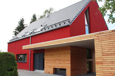 Modernes Einfamilienhaus mit Putzfassade, roter Fassadenfarbe, Satteldach, Ziegeldach und grauem Dach in München