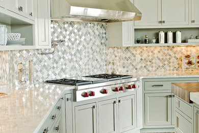 Large l-shaped medium tone wood floor enclosed kitchen photo in Portland with an undermount sink, recessed-panel cabinets, wood countertops, white backsplash, glass tile backsplash, stainless steel appliances and an island