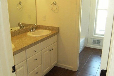 Mid-sized transitional 3/4 ceramic tile bathroom photo in New York with recessed-panel cabinets, white cabinets, a two-piece toilet, white walls, a drop-in sink and granite countertops