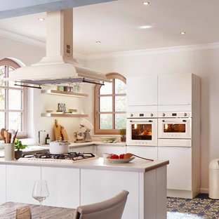 Photo of a mid-sized midcentury u-shaped open plan kitchen in Other with a double-bowl sink, flat-panel cabinets, white cabinets, laminate benchtops, white splashback, coloured appliances, porcelain floors, no island, blue floor and beige benchtop.