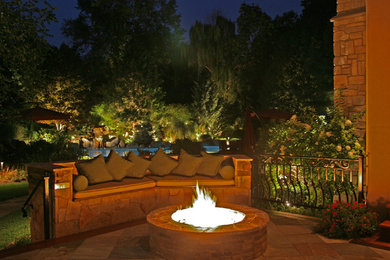 Large elegant backyard stone patio photo in New York with a fire pit and a pergola