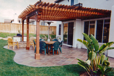 Inspiration for a large tropical backyard stone patio kitchen remodel in San Diego with a pergola