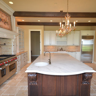 Large traditional kitchen pantry pictures - Kitchen pantry - large traditional l-shaped travertine floor kitchen pantry idea in Louisville with an undermount sink, glass-front cabinets, white cabinets, quartzite countertops, beige backsplash, stone tile backsplash, stainless steel appliances and an island