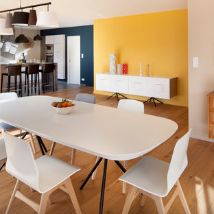 На фото: большая гостиная-столовая в современном стиле с светлым паркетным полом и желтыми стенами без камина с