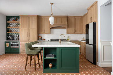 Eat-in kitchen - mid-sized mediterranean l-shaped terra-cotta tile and brown floor eat-in kitchen idea in Los Angeles with a drop-in sink, shaker cabinets, light wood cabinets, quartz countertops, white backsplash, quartz backsplash, stainless steel appliances, an island and white countertops