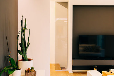 Идея дизайна: большая открытая гостиная комната в стиле модернизм с серыми стенами, светлым паркетным полом и телевизором на стене без камина