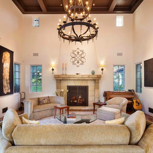 Diseño de salón con rincón musical mediterráneo, grande, con paredes blancas, suelo de madera en tonos medios, chimenea tradicional y marco de chimenea de piedra
