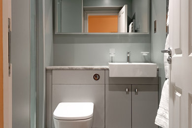 This is an example of a small contemporary ensuite bathroom in Glasgow with flat-panel cabinets, grey cabinets, a walk-in shower, a one-piece toilet, green tiles, green walls, vinyl flooring, a built-in sink, laminate worktops, grey floors, an open shower, grey worktops, a feature wall, a single sink, a built in vanity unit, a drop ceiling and panelled walls.