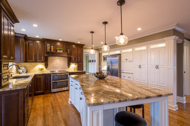 Inspiration for a large timeless galley medium tone wood floor enclosed kitchen remodel in Louisville with an undermount sink, raised-panel cabinets, dark wood cabinets, marble countertops, beige backsplash, stone tile backsplash, black appliances and an island