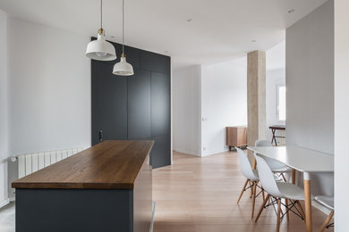 Inspiration for a mid-sized scandinavian l-shaped open plan kitchen in Valencia with a single-bowl sink, flat-panel cabinets, black cabinets, wood benchtops, stainless steel appliances and with island.