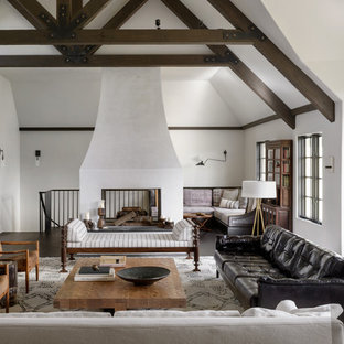 Imagen de salón abierto, mediterráneo, con paredes blancas, suelo de madera oscura, chimenea de doble cara y suelo marrón