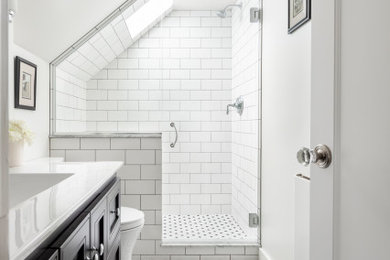 シアトルにあるお手頃価格の中くらいなトランジショナルスタイルのおしゃれなバスルーム (浴槽なし) (落し込みパネル扉のキャビネット、濃色木目調キャビネット、アルコーブ型シャワー、分離型トイレ、白いタイル、セラミックタイル、白い壁、セラミックタイルの床、一体型シンク、人工大理石カウンター、白い床、開き戸のシャワー、白い洗面カウンター、洗面台1つ、造り付け洗面台、三角天井) の写真