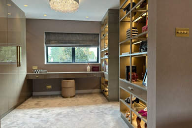This is an example of a medium sized dressing room for women in West Midlands with flat-panel cabinets and carpet.