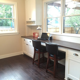 Medium sized modern craft room in Minneapolis with beige walls, dark hardwood flooring, no fireplace, a built-in desk and black floors.