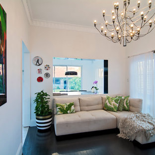 Imagen de sala de estar tropical, pequeña, sin chimenea y televisor, con paredes blancas, suelo de madera oscura y suelo negro