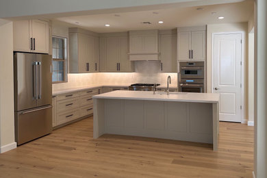 Inspiration for a mid-sized transitional kitchen remodel in Phoenix with an undermount sink, shaker cabinets, white backsplash, porcelain backsplash, stainless steel appliances and an island