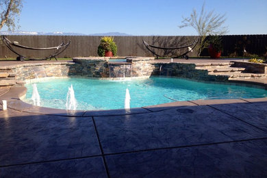 Inspiration for a large tropical backyard custom-shaped pool in Orange County with a hot tub and stamped concrete.