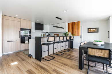 Example of a mid-sized mid-century modern u-shaped open concept kitchen design in Portland with flat-panel cabinets, light wood cabinets, quartz countertops, white backsplash, white countertops and no island