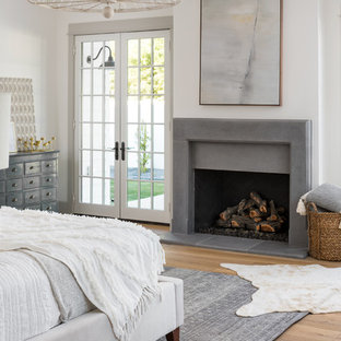 Неиссякаемый источник вдохновения для домашнего уюта: большая хозяйская спальня в стиле кантри с белыми стенами, светлым паркетным полом, стандартным камином, фасадом камина из бетона и коричневым полом