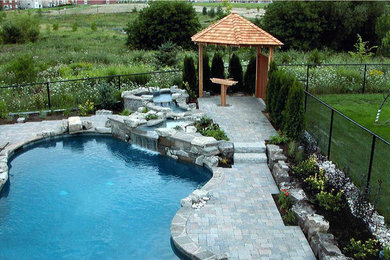 Pool fountain - large backyard stone and custom-shaped natural pool fountain idea in Toronto
